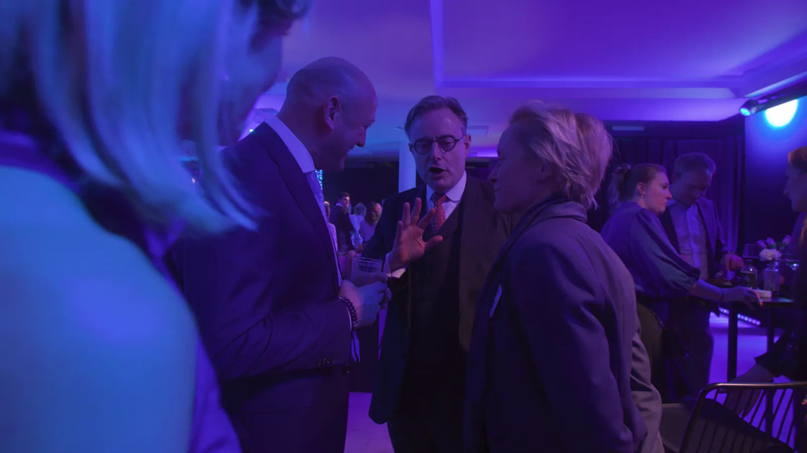 Beeld uit de Blue-aftermovie: gasten in gesprek op de receptie na de show, de hele zaal in blauw licht.